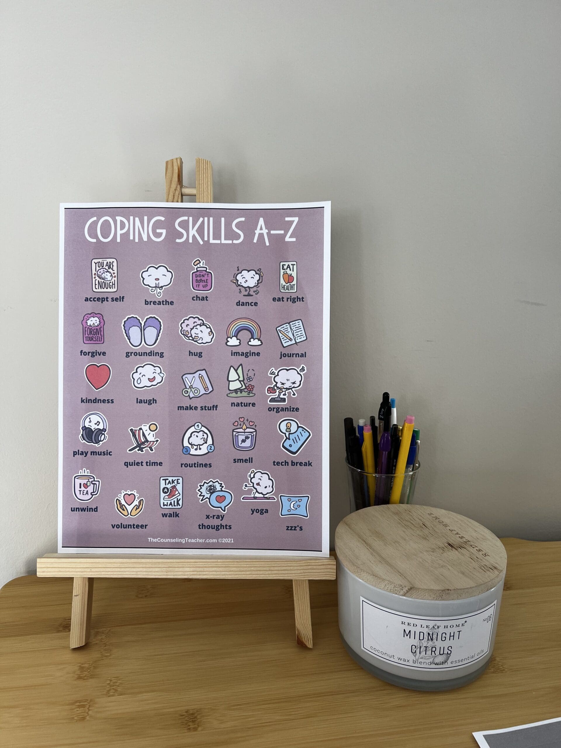 Coping skills A-Z poster displayed on a wooden easel in a counseling office, showing colorful illustrated strategies like breathing, grounding, journaling, and practicing kindness. Franklin and Brentwood, TN therapy space.