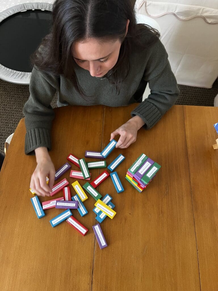 Therapist facilitating a coping skills and feelings conversation game with colorful Jenga-style blocks during a therapy session, supporting emotional regulation and communication for children and teens.
