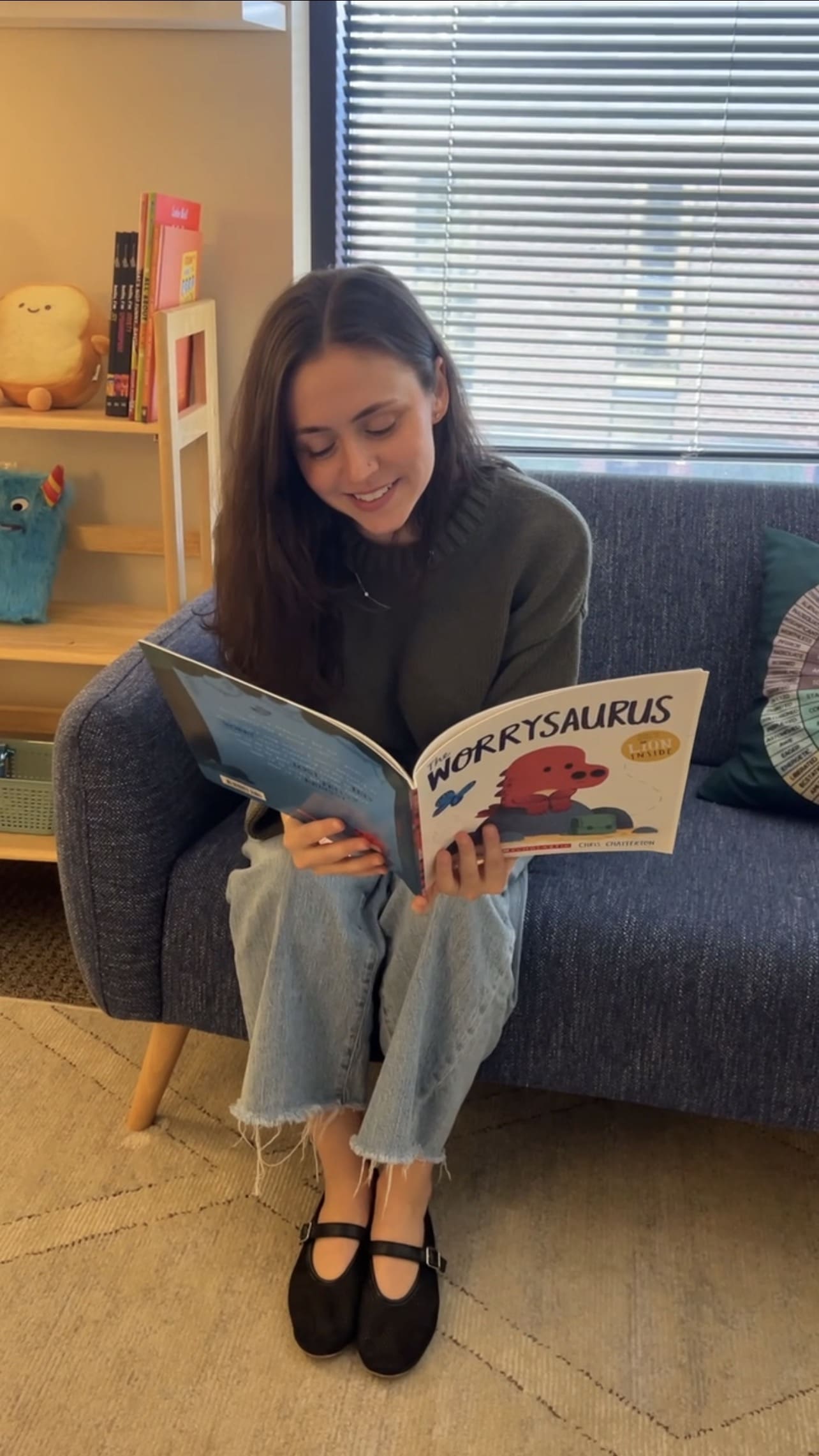 Therapist reading ‘The Worrysaurus’ picture book to support children in understanding anxiety and calming worries during play-based therapy in a Brentwood, TN counseling office.